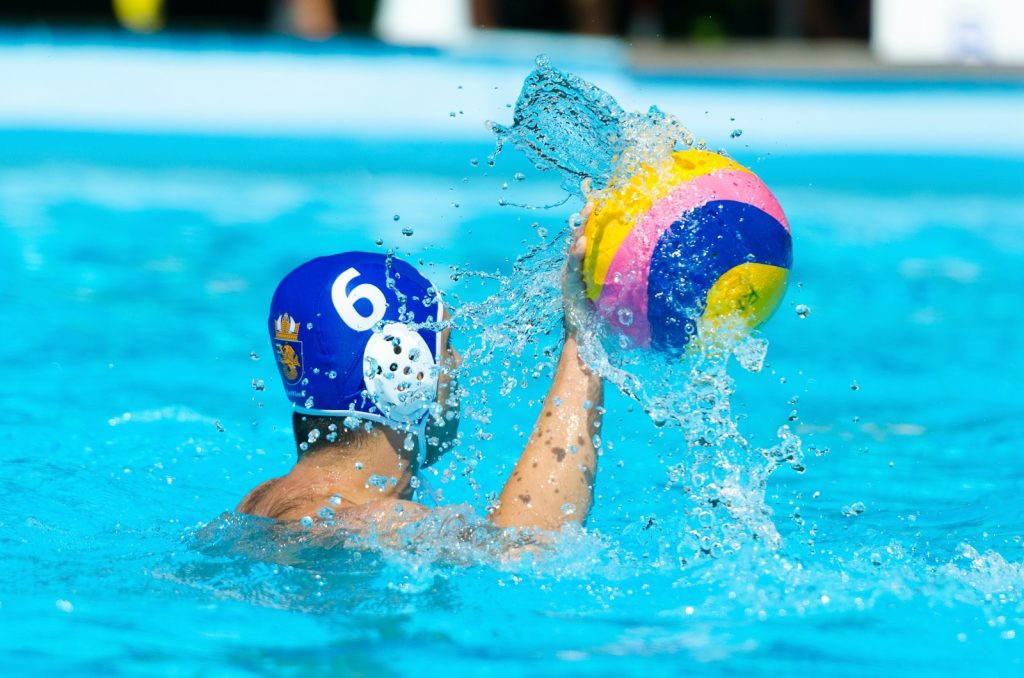 person swimming in pool with multi color inflatable ball