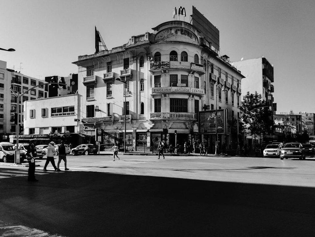 Black and white photo of a historic building in Kenitra, Morocco with people and traffic.