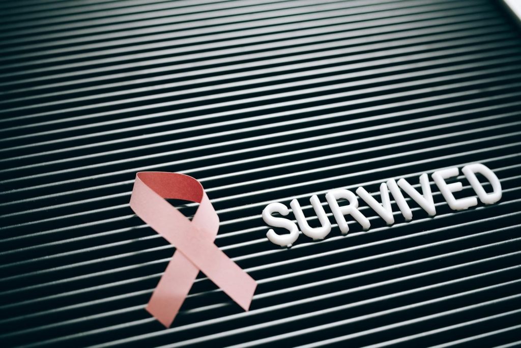 Conceptual image of breast cancer survival with pink ribbon and 'Survived' message.