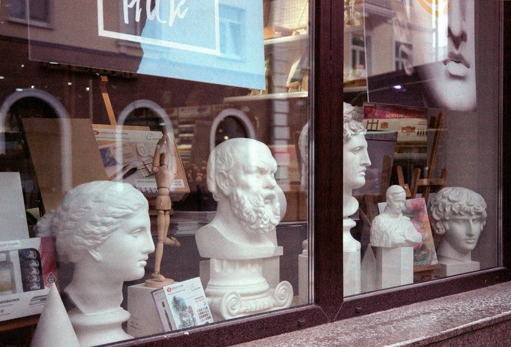 A storefront display featuring classical sculpture busts and art supplies.