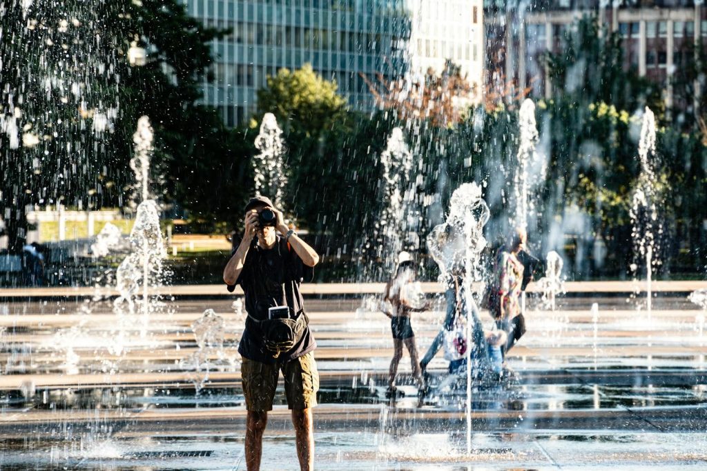 Urban photographer captures vibrant city fountain scene on a sunny day.