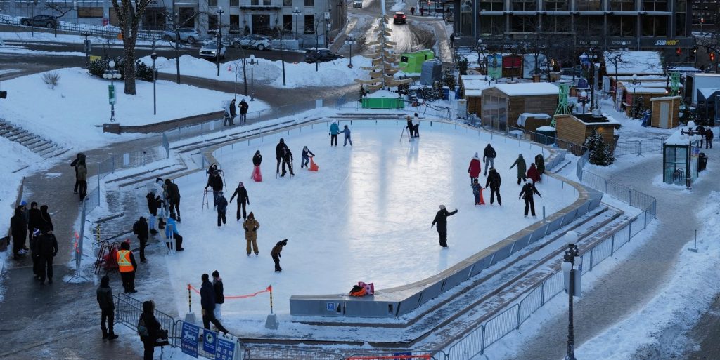 People ice skating in a snowy city square.