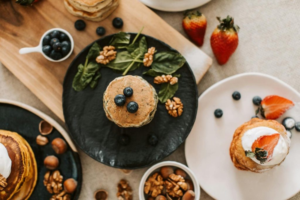Overhead shot of pancakes with blueberries, strawberries, and walnuts for breakfast.