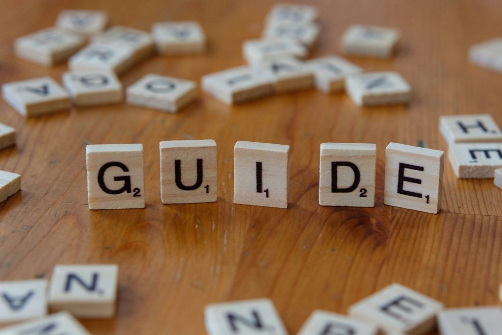 A wooden table topped with scrabble tiles spelling the word guide