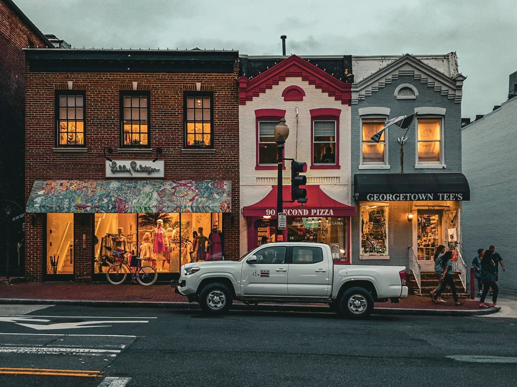 Shops and a truck line a colorful street.