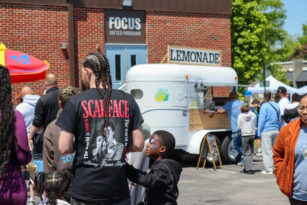 People gather near a lemonade stand on a sunny day.