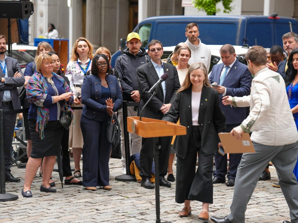 A woman speaks at a podium to a crowd outdoors.