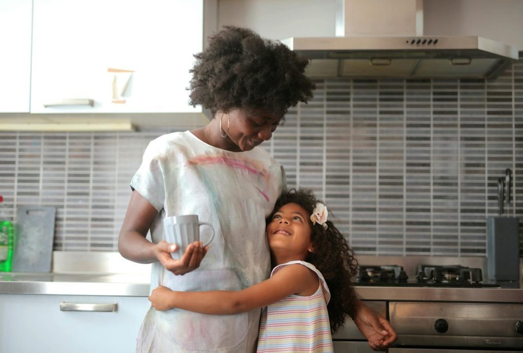 A joyful moment between mother and daughter in a modern kitchen setting.