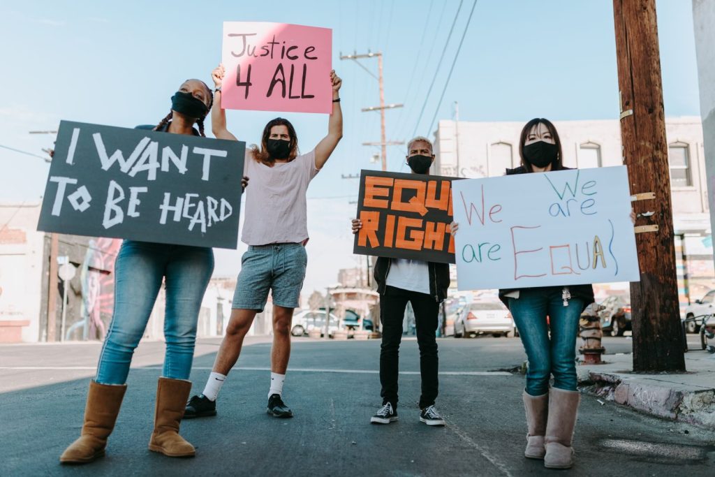 A diverse group holding equality signs during a peaceful protest in an urban setting.