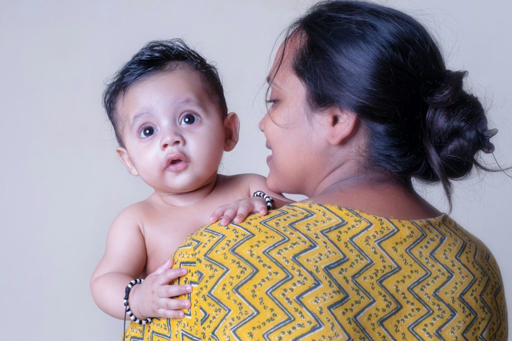 A woman holds a baby looking directly at the camera.