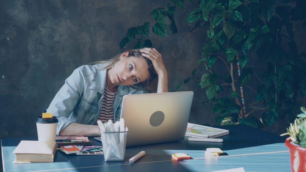A woman appears stressed while working on laptop about bills
