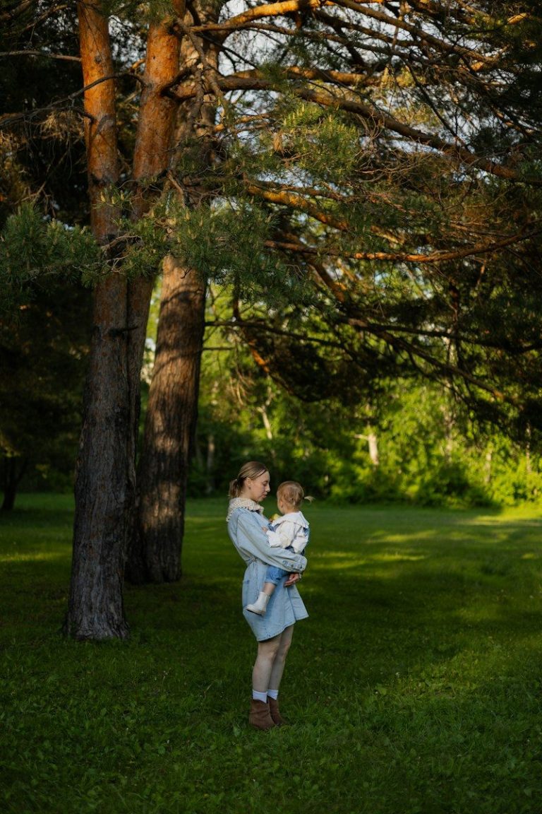Woman holding a baby in a sunlit park