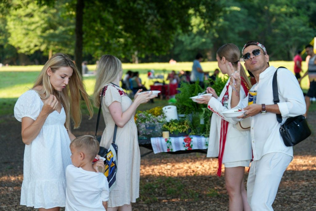 A group of people eating at a picnic in a sunlit park