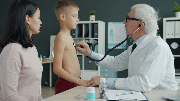 Doctor examining a boy while his mother watches