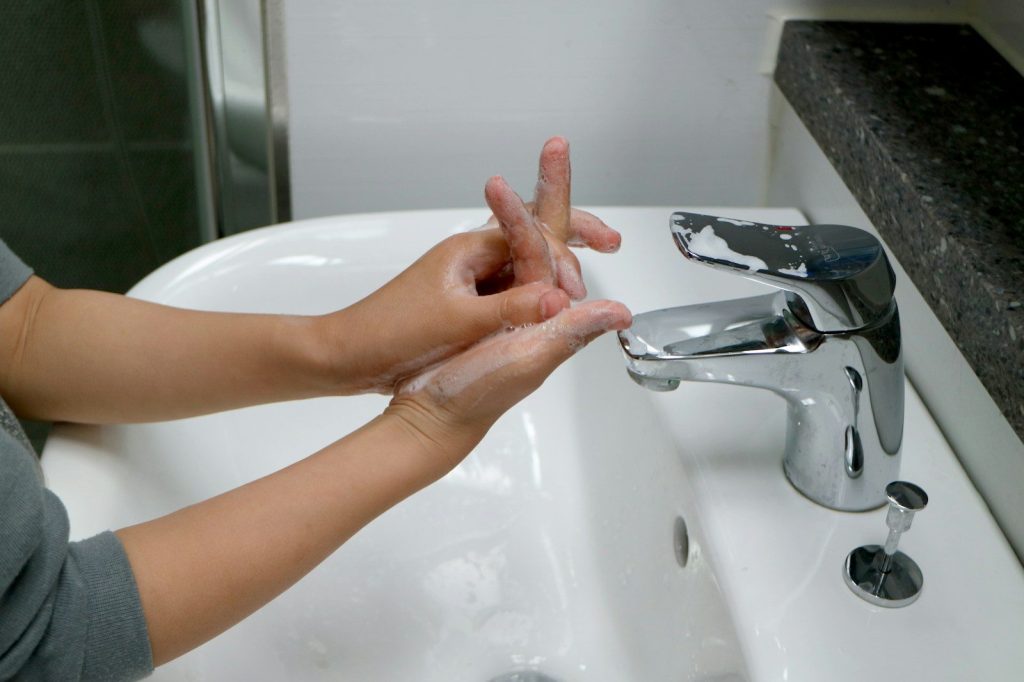A woman washing her hands in a bathroom sink