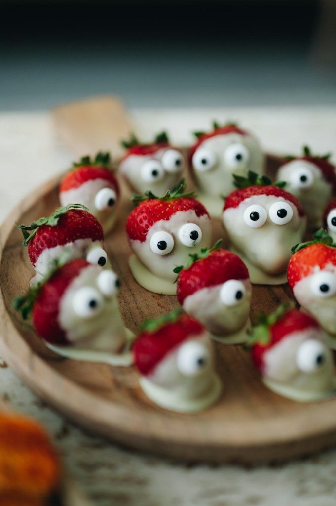 a wooden plate topped with strawberries covered in googly eyes
